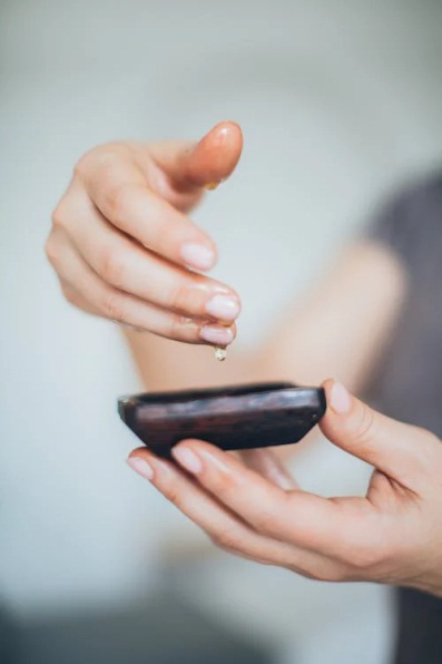 An image of a person holding a saucer and taking oil from it