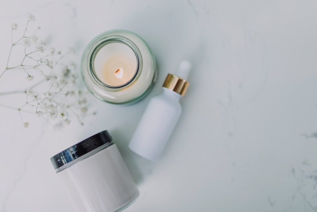 An image of a candle, a white bottle, and a white jar