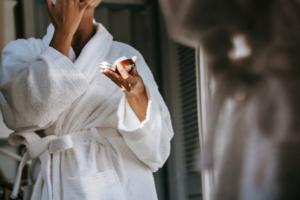woman in a bathrobe holding a small container