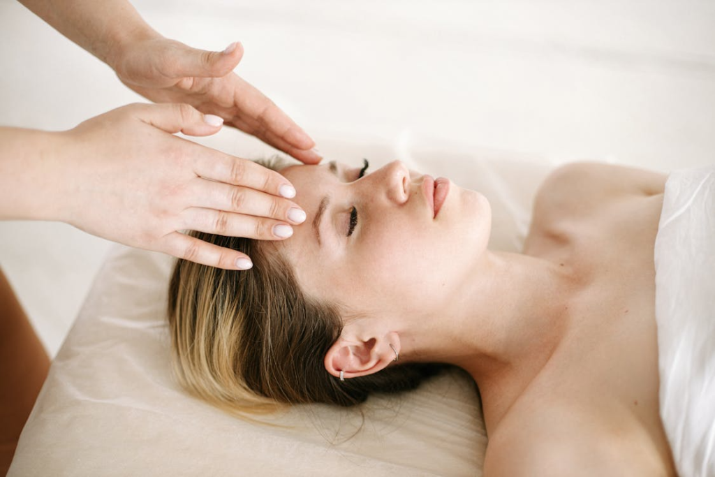 a woman lying down on a massage table getting a head massage