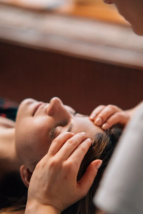 close-up of a woman's head getting a massage over pressure points by a masseuse
