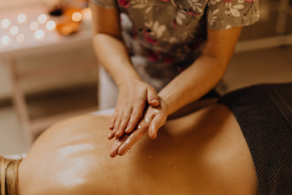 close-up of a massage therapist's hands as she rubs oil between them over a client's back