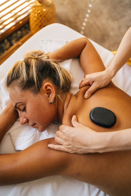 Woman receiving a hot stone massage with heated stones placed on her back
