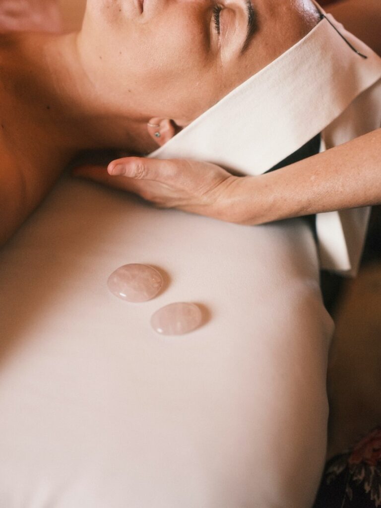 Therapist performing a soothing facial massage with warm stones to enhance relaxation.
