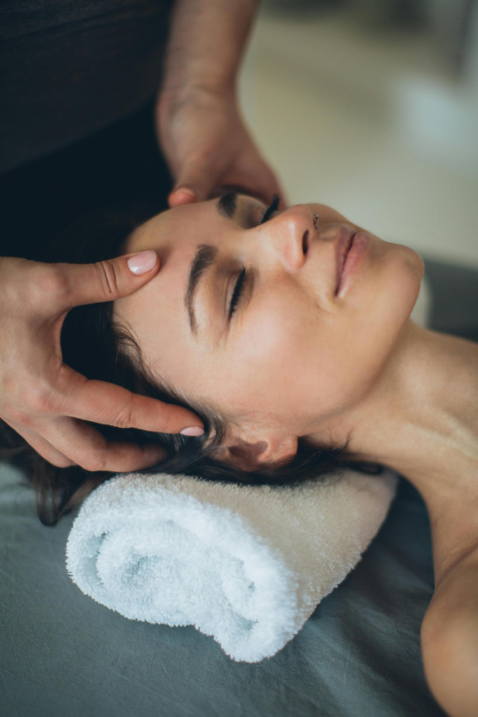 Woman receiving relaxing head and facial massage at professional spa