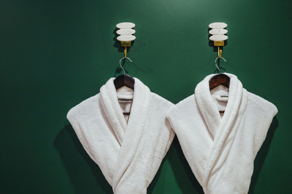two white robes hung against a green wall