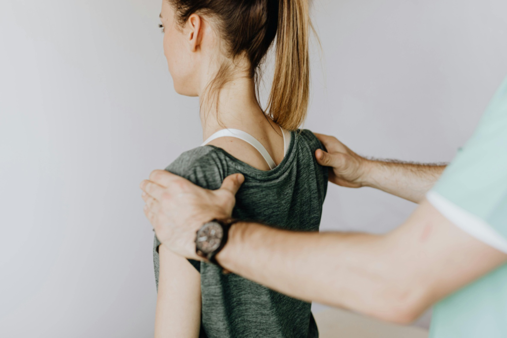  a massage therapist correcting a client’s posture by holding their shoulders