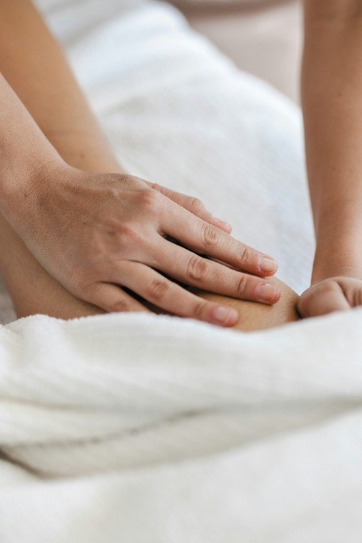 Hands performing a deep tissue massage on a client’s leg muscle