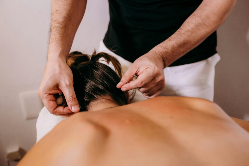 An image a massage therapist massaging a client in grey trousers