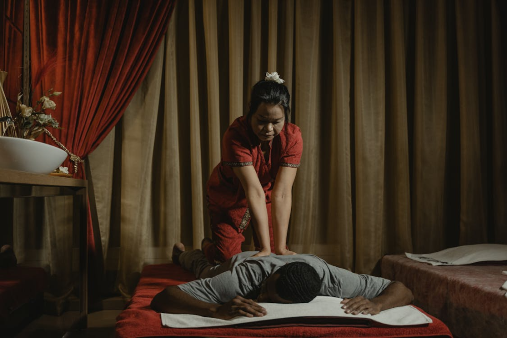 a person getting a Thai massage from a masseur in red attire