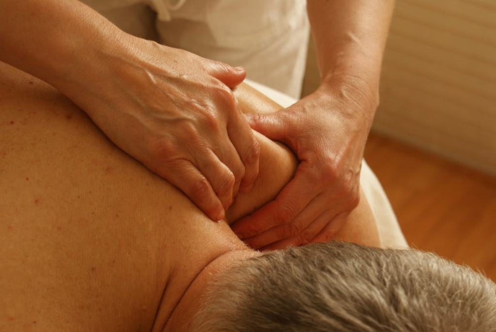 This photo shows a person getting a massage on his shoulder. 
