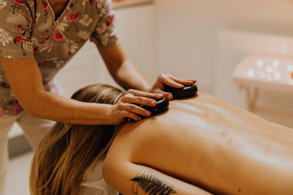 a masseuse using stones to massage a person's back