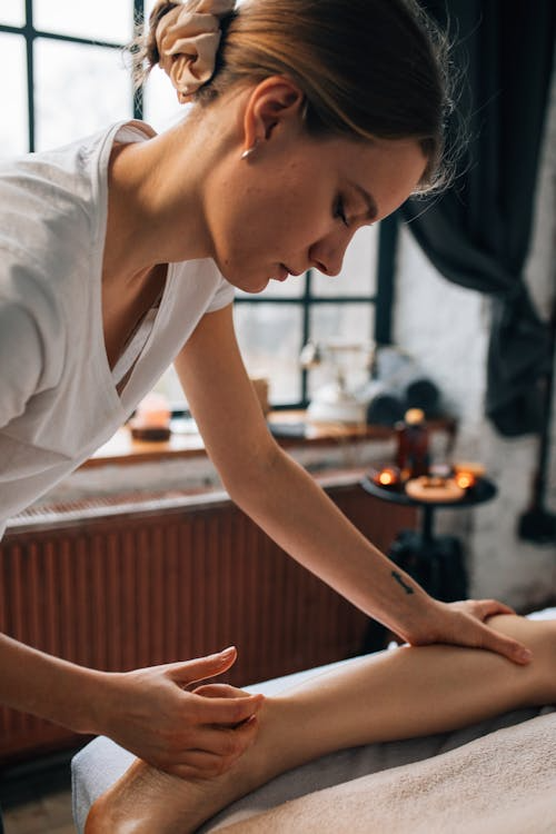 a massage therapist working on a person’s leg during a recovery-focused treatment