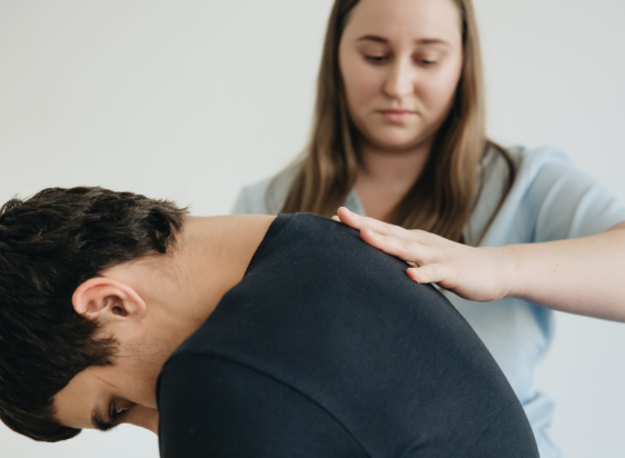 This image shows a person receiving massage treatment for neck and upper back tension.