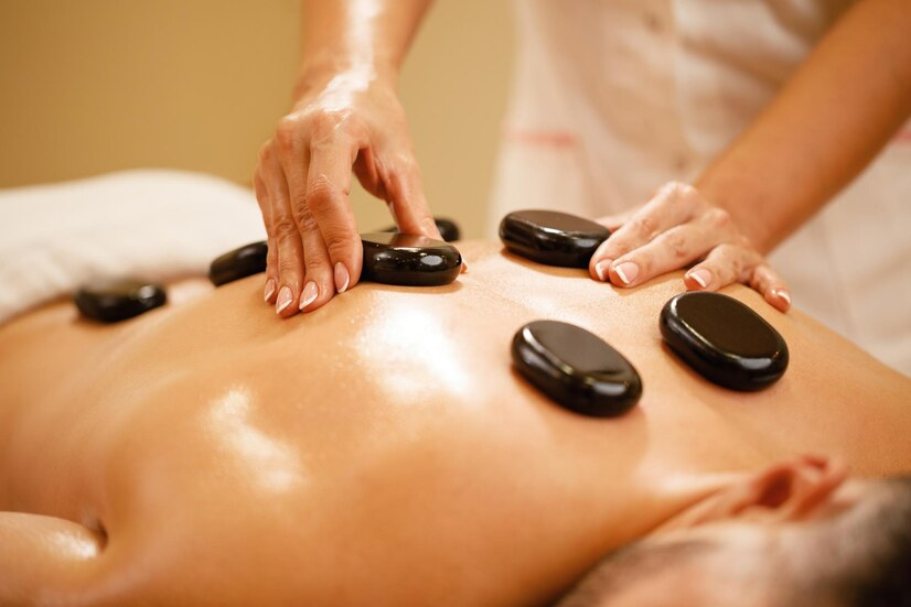 a massage therapist placing hot stones on a person’s back