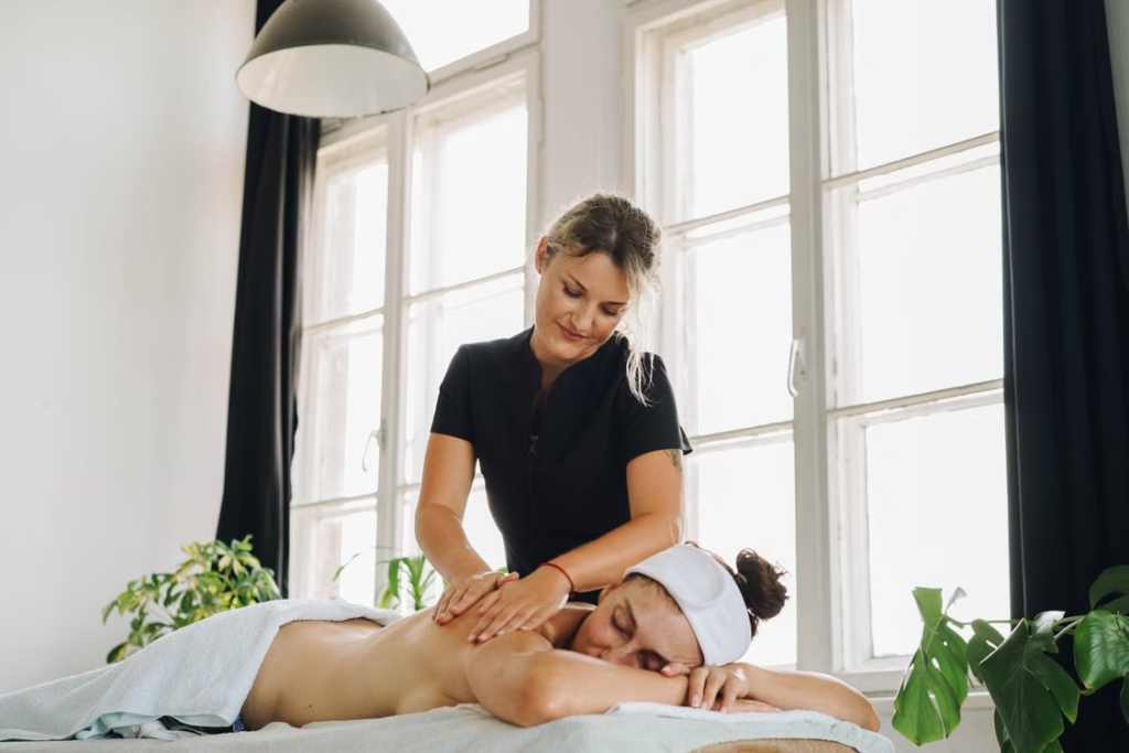 A woman massaging another person’s back. 